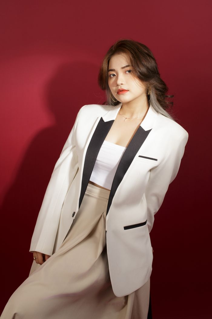 about-us-01 Stylish portrait of a well-dressed woman in formalwear with a red backdrop, showcasing elegance and fashion.