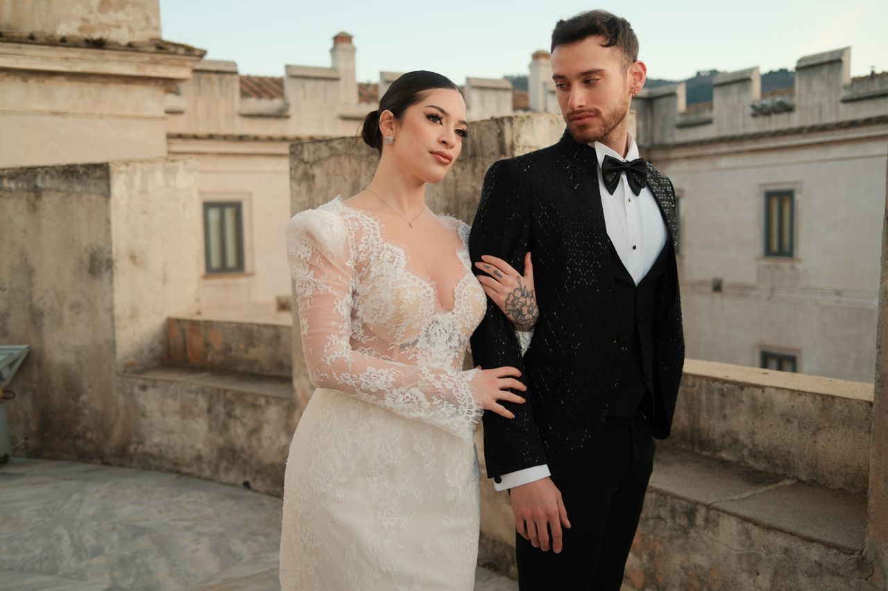 heros-img Stylish bride and groom pose against a historic stone venue, showcasing modern elegance and romance.